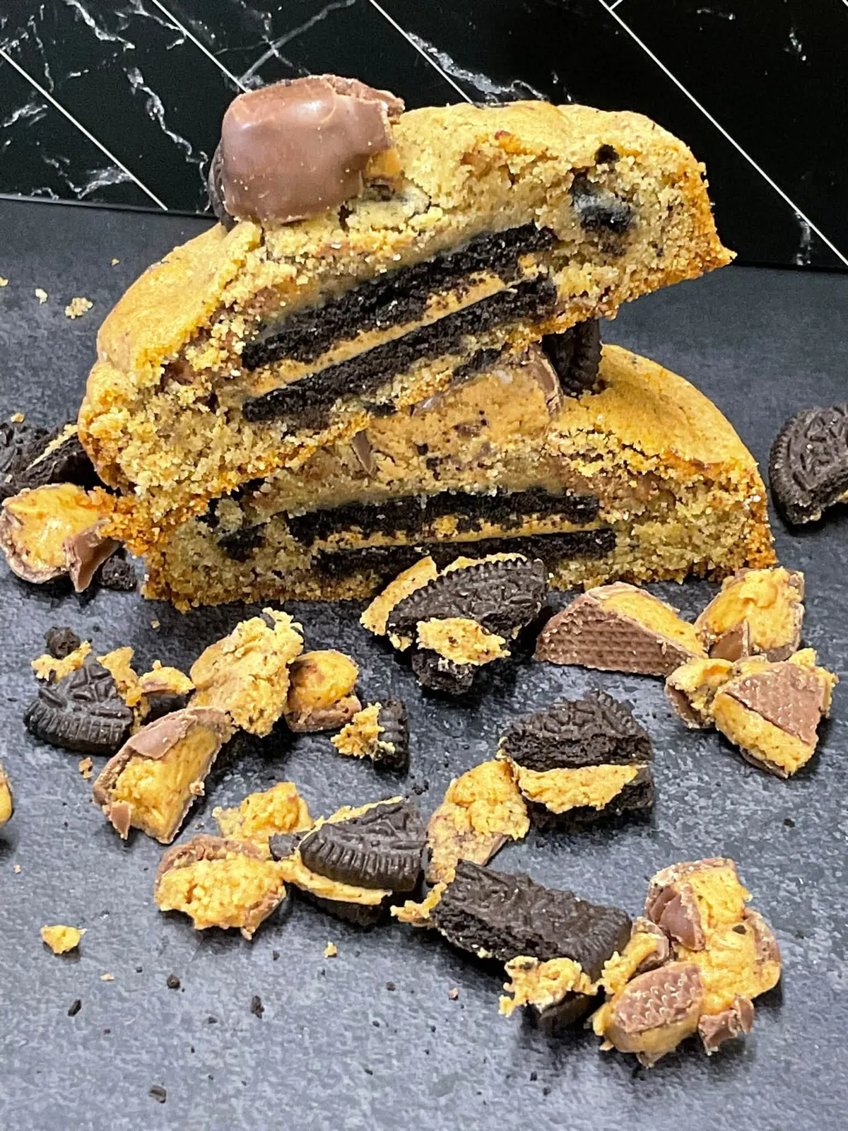 Cookies & cream peanut butter cup cookie split open to show Oreo layers inside