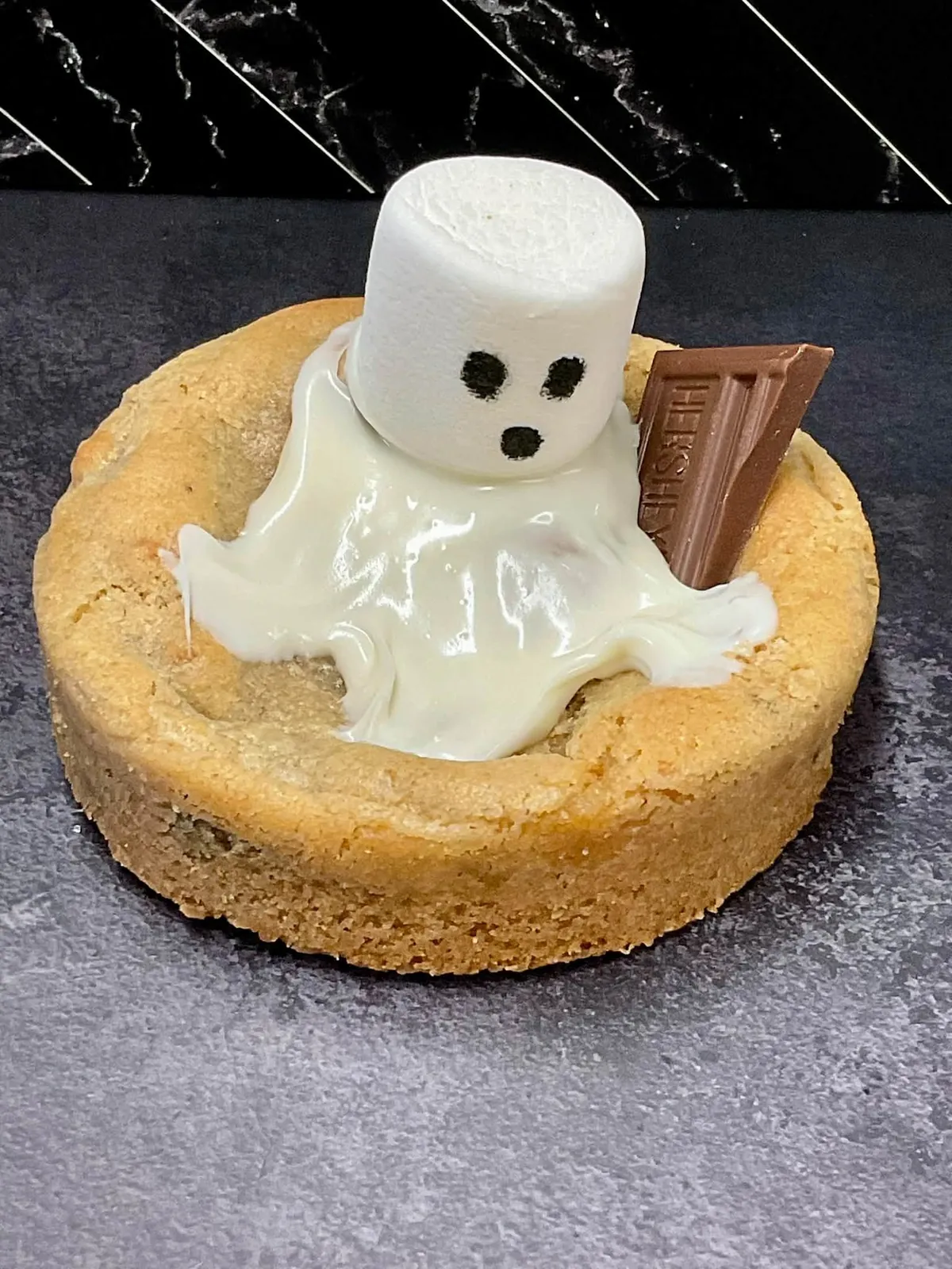 Ghost S'mores cookie topped with a marshmallow ghost and a Hershey's square